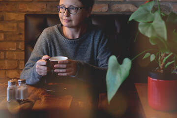 Woman is enjoying a cup of coffee in a cozy cafe or restaurant 