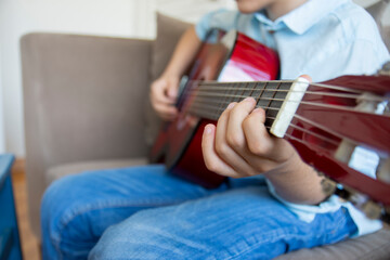 little boy playing guitar. close up of fingers and guitar frets
