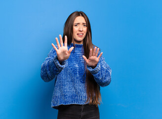 young pretty casual woman feeling terrified, backing off and screaming in horror and panic,...