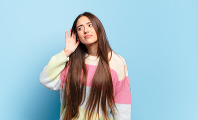 young pretty casual woman looking serious and curious, listening, trying to hear a secret...