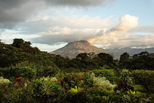 Dramatic photo of Arenal volcano with tropical vegetation in front during sunset. Costa Rica.