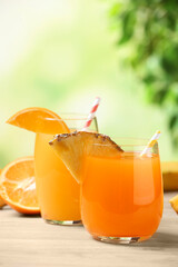 Pineapple and orange juices in glasses on white table