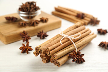 Aromatic cinnamon sticks and anise on white wooden table