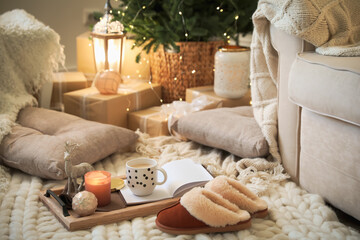 Wooden tray with cocoa, candle and notebook in room decorated for Christmas