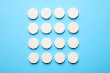 White pills on light blue background, flat lay