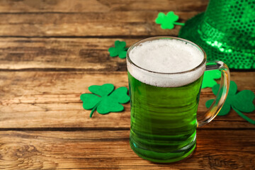 Green beer and St Patrick's Day decor on wooden table. Space for text
