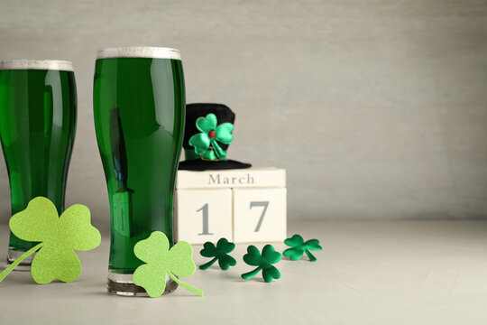 Green beer and St Patrick's Day decor on light table. Space for text