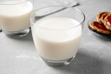 Glass of delicious milk on grey table