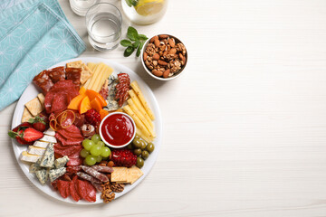 Plate of different appetizers with dip sauce on white wooden table, flat lay. Space for text
