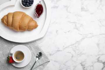 Tasty breakfast with fresh croissant and aromatic coffee on white marble table, flat lay. Space for text