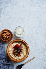 a bowl of oats with nuts and dried fruits in white background