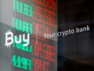 words Buy Your crypto bank on a office window on the background of glowing currency exchange rates on a window of a crypto bank office, in Kiev, Ukraine, on 22 October 2018.