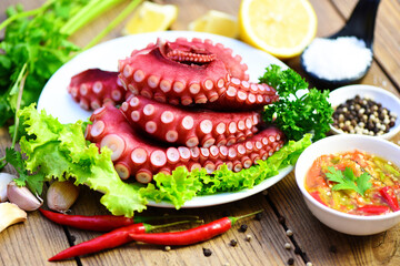 Boiled octopus tentacles, Octopus food on wooden cutting board background, cooked squid salad chili sauce seafood cuttlefish dinner restaurant.