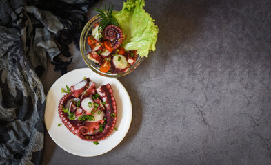 Fresh and healthy salad seafood squid and octopus tentacles, Octopus salad vegetables with lemon lime tomatoes chili herbs and spice on plate and bowl