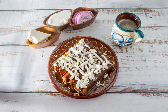 Enchiladas or mole wraps with a Mexican cup of coffee, purple onion, cream and fresh cheese. Mexican food, Mexican coffee
