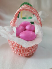 One large pink crocheted Easter Basket filled with pink chocolate-covered Easter eggs. 