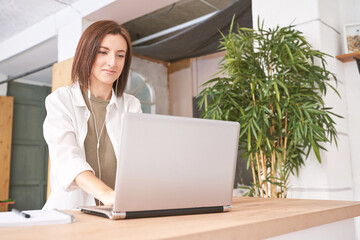 Young woman sitting at home. Working on notebook. Online study concept. Safety lockdown distance...