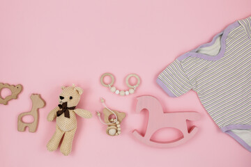 Wooden pyramid, toys, a horse on pastel pink background. Trendy cute baby first toys. Eco-friendly, plastic-free set of accessories for kids. Toys for kindergarten, preschool or daycare. Close up