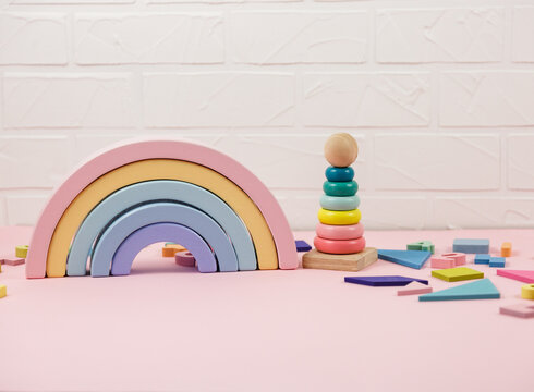Wooden pyramid, toys, a horse on pastel pink background. Trendy cute baby first toys. Eco-friendly, plastic-free set of accessories for kids. Toys for kindergarten, preschool or daycare. Close up