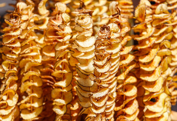 Golden potato chips, cut into slices, on a thin wooden stick close up. food background