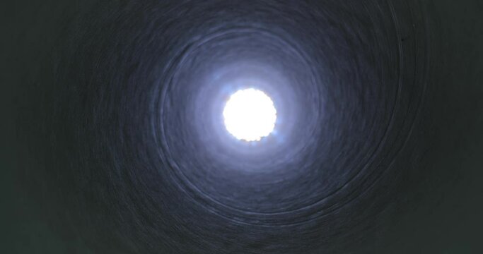 Moving through a tube tunnel with bright light shining at the end, probe lens motion, rising in shaft