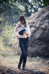 A girl in a cowboy hat on the background of a haystack at sunset