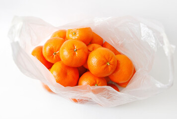 fresh mandarin citrus fruit in an opened plastic bag on white background