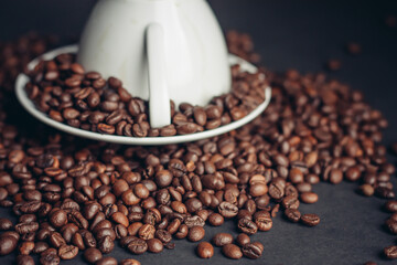 coffee beans white saucer and an inverted cup close-up dark background top view