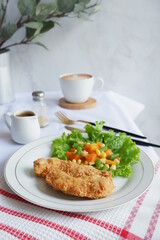 a plate of crispy chicken steak and vegetables with black pepper sauce in white background 