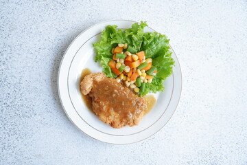a plate of crispy chicken steak and vegetables with black pepper sauce in white background 