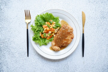 a plate of crispy chicken steak and vegetables with black pepper sauce in white background 