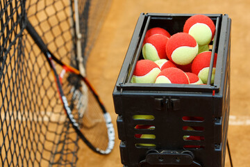 basket of tennis balls closeup, tennis racket and grid for tennis. tennis court. selective focus.