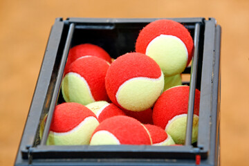 basket with a lot of red and green tennis balls closeup. tennis court. selective focus