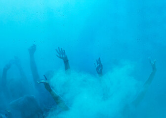 human hands raised up in a mist of blue paint, background