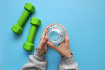 Two sports dumbbells and water in the hands of a person. Sports and healthy lifestyle in the modern world