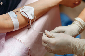 Gentle hands of a nurse taking blood from a patient's vein. Close-up. Gloves on the hands of a...