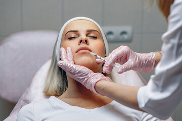 Cosmetic procedures for face rejuvenation. Lip augmentation Botox injections. Master beautician...