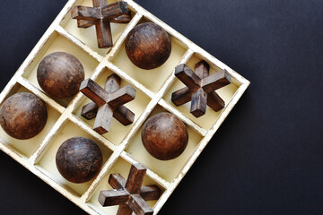 A top view image of an old fashioned tic tac toe game on a black background. 