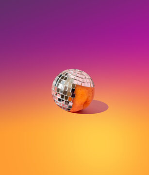 Peach in a disco ball on a yellow-pink gradient background. Creative concept