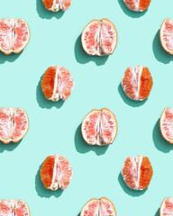 Colorful fruit pattern from fresh red grapefruit half path on turquoise. Minimal flat lay concept.