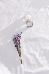 Balsam with  lavender essential oil and dry flowers on white bedclothes. Scent of lavender improves sleep and alleviates insomnia.