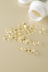 vitamin D capsules poured from packaging on a light background