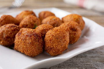 A closeup view of a plate of deep fried hush puppies.