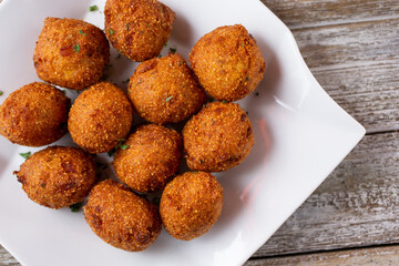 A top down view of a plate of deep fried hush puppies.