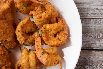 A top down view of a plate of deep fried shrimp and deep fried fish.