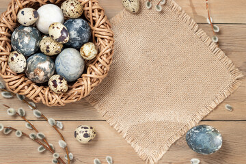 Fototapeta na wymiar Easter composition - Easter eggs painted with natural dyes in a wicker nest on a wooden table, copyspace