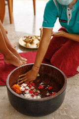 Closeup photo of female feet at spa salon on pedicure procedure. Female legs in water decoration flowers and getting massage