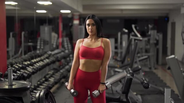 sexy girl with dumbbells posing in front of the camera and smiling