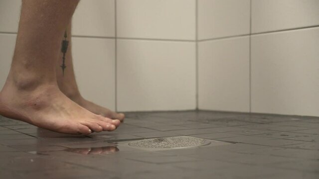Caucasian male starts to shower at home, close up shot of feet and floor