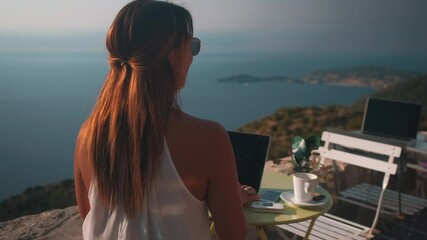 Slow dolly zoom in of beautiful luxury girl working on laptop with epic ocean view during sunlight. Drinking coffee and Working on holidays. Close up.